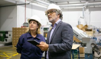 Confident bearded supervisor talking with female plant worker