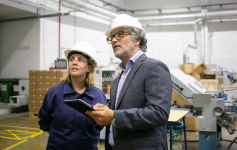 Confident bearded supervisor talking with female plant worker